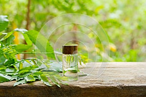 Neem oil in bottle and fresh neem leaf on wooden.