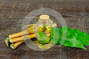 Neem oil in bottle and neem leaf on wooden background.