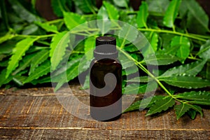 Neem oil in bottle on wooden background.