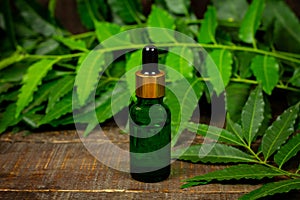 Neem oil in bottle on wooden background.