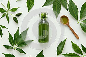 Neem oil with fresh leaves on white background