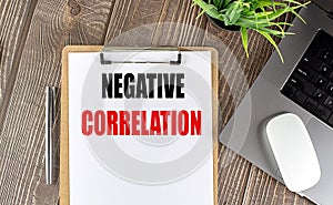 NEGATIVE CORRELATION text on clipboard paper with laptop, mouse and pen photo