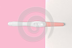 Negative plastic pregnancy test on pink and white background.