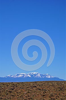 Negative space above desert, snow covered mountains and blue sky