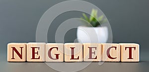 NEGLECT - word on wooden cubes on a gray background with a cactus