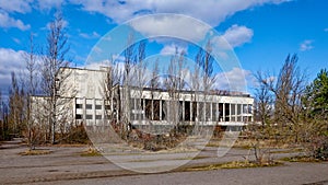 A neglected building, once white, now stained and crumbling amidst wild growth. The Energetik Palace of Culture is a now abandoned