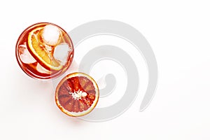 Negroni alcoholic cocktail with dry gin, red vermouth and red bitter, bloody orange slice and ice cubes. White background, steel