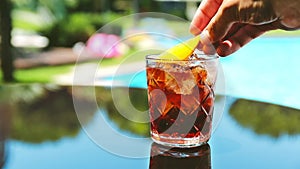 Negroni cocktail at the resort bar or suite patio. Luxury resort, vacation, room service concept. Adding orange slice