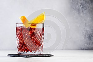 Negroni popular alcoholic cocktail with dry gin, red vermouth and red bitter, orange slice and ice cubes. Gray bar counter