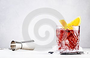 Negroni popular alcoholic cocktail with dry gin, red vermouth and red bitter, orange slice and ice cubes. Gray bar counter