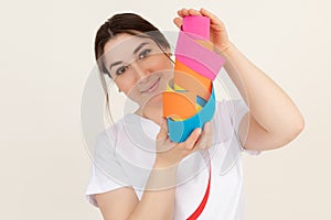 Neighborly woman, therapist, doctor look at camera, showing, advertising colorful kinesio tapes for manual application