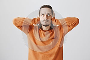 Neighbors arranged loud party. Portrait of angry annoyed young man with beard, holding up, covering ears with palms