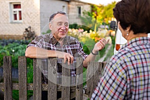 Neighbors man and woman chatting near the fence in the village