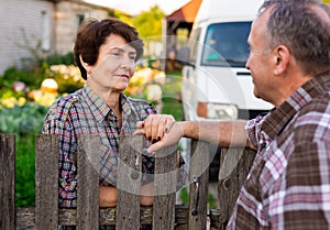 neighbors man and woman chatting near the fence in the village