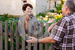 neighbors man and woman chatting near the fence in the village