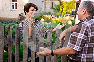 Neighbors man and woman chatting near the fence in the village