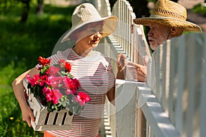 Neighbors standing near fence talking about planting flowers