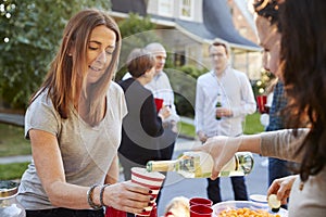 Neighbour pouring a woman a cup of wine at a block party