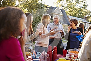 Neighbours talk and eat at a block party, close up