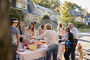 Neighbours talk standing around a table at a block party photo