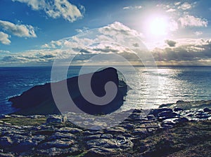 Neist Point lighthouse on rocky cliff above wavy sea. Blue evening sea and sharp cliffs,