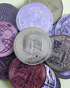 neo cryptocurrency coin on the background of multicolored coins of various cryptocurrencies close up