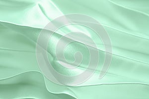 Neo mint color soft satin folded fabric background texture. Close up of ripples on silk fabric. Neo mint color 2020 year concept.