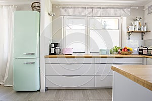 Neo mint fridge standing in real photo of bright kitchen interio photo