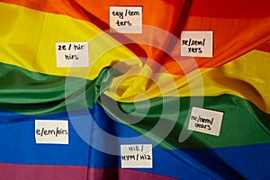Neo pronouns concept. Rainbow flag with paper notes text gender pronouns hie, e, ne, xe, ze, tey. Non-binary people