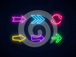 Neon arrow signs set. Bright arrow pointer symbols on brick wall background. Collection of colorful neon arrows