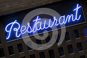 Neon blue restaurant sign lit up at night closeup