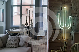 neon cactus sign hanging in a modern apartment living room