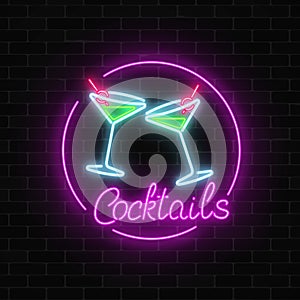 Neon cocktails bar sign on dark brick wall background. Glowing gas advertising with glasses of alcohol shake.