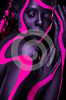 Neon colors. Pink and black body paint. Woman with face art. Young girl with colorful bodypaint. An amazing afro