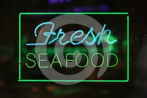 Neon Fresh Seafood Sign in Rainy Window