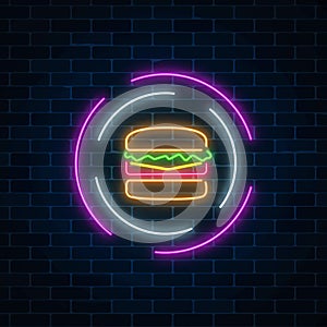 Neon glowing burger sign in circle frames on a dark brick wall background. Fastfood light billboard symbol.