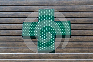 Neon green cross sign on wooden background