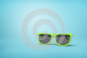 Neon green sunglasses on light blue backdrop