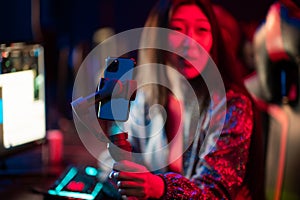 Neon light in the esports arena. Portrait of a young asian girl with a gimbal, who records a video blog content on a