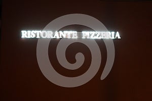 Neon lights inscription in Italian saying pizza restaurant or pizzeria.