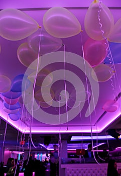 Neon lit purple ceiling with many party balloons