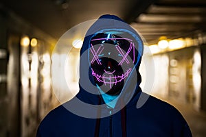 Neon masked criminal on the dark. Selective focus