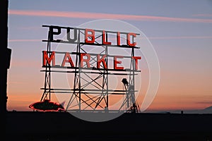 Neon public market sign at Pike Place Market and Elliott bay during the sunset