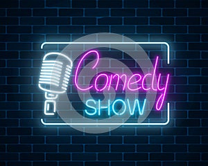 Neon sign of comedy show with retro microphone symbol on a brick wall background. Humor glowing signboard.