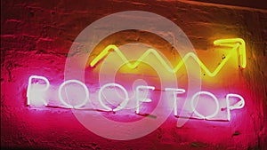 Neon sign saying Rooftop bar upstairs, nightlife, alcohol, and cocktails