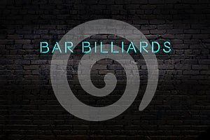 Neon sign. Word bar billiards against brick wall. Night view