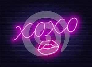 Neon sign xoxo with a kiss on a dark background.