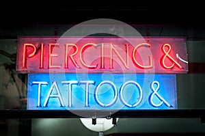 Neon signboard with Piercing & Tattoo at night.