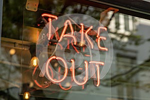 Neon Take Out sign behind a window, take out neon is to draw attention for customers