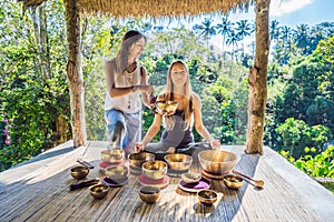 Nepal Buddha copper singing bowl at spa salon. Young beautiful woman doing massage therapy singing bowls in the Spa